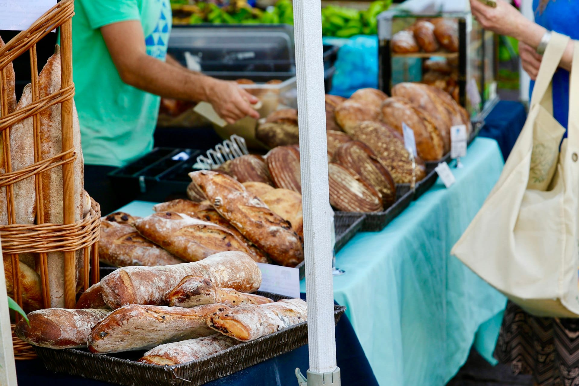A vendor handing fresh sourdough across a farmers market table