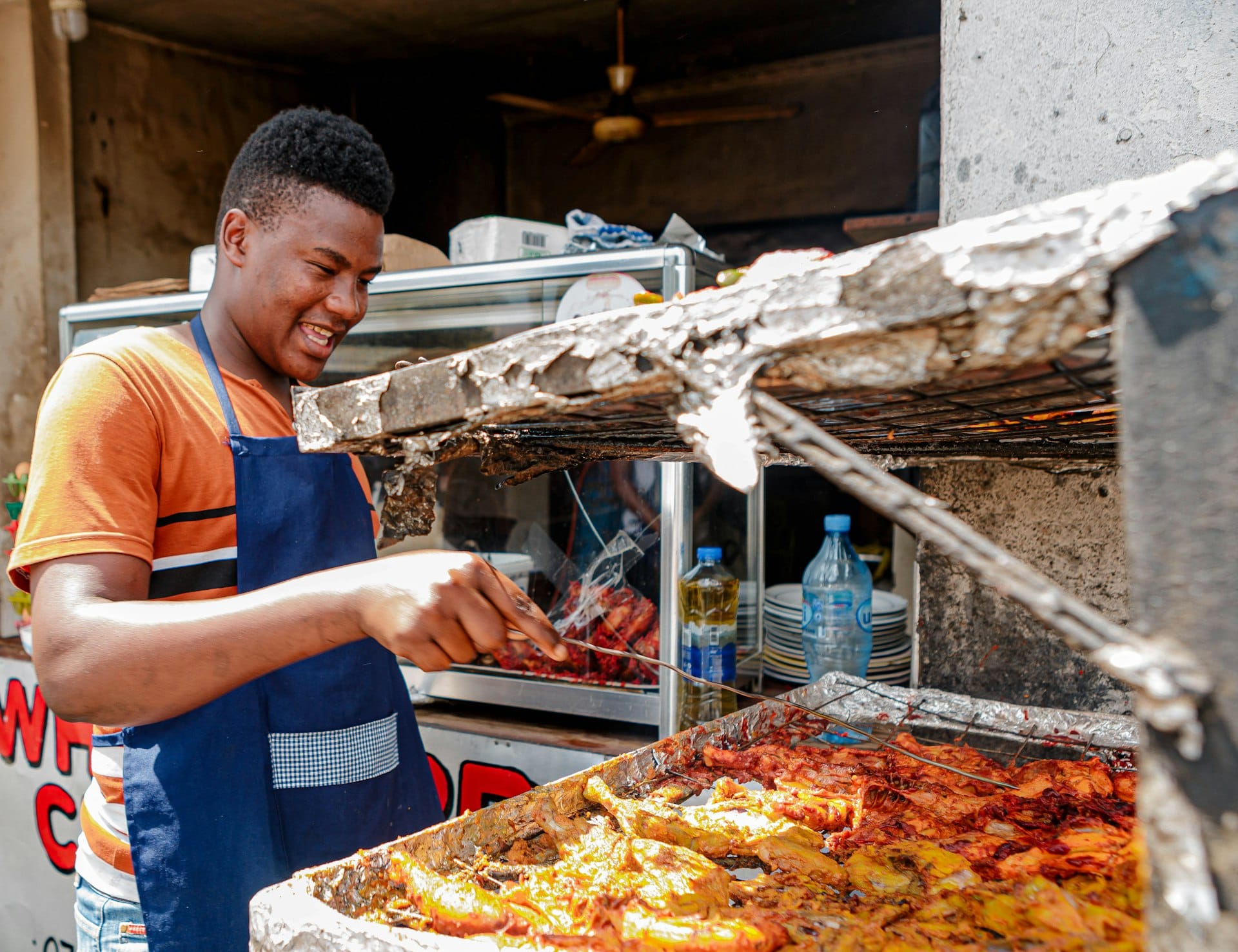 A vendor grilling chicken at an outdoor food stand
