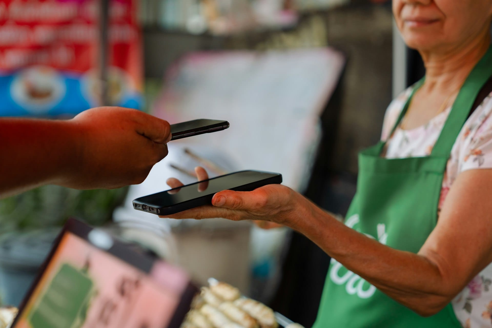 A vendor and customer trading phones at a market stall