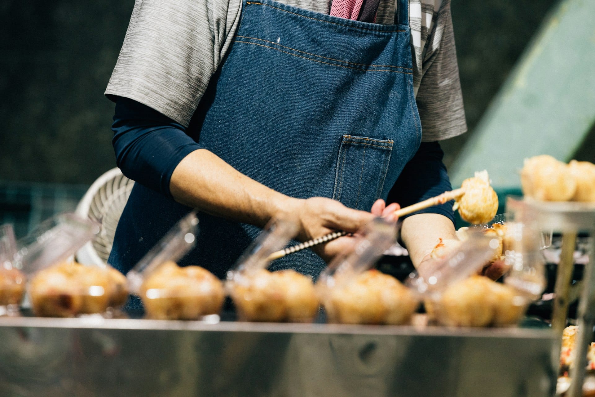 A maker plating skewered bites at an event stall